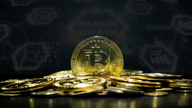 A physical golden Bitcoin token sitting upright on top of a pile of gold coins with a blockchain background